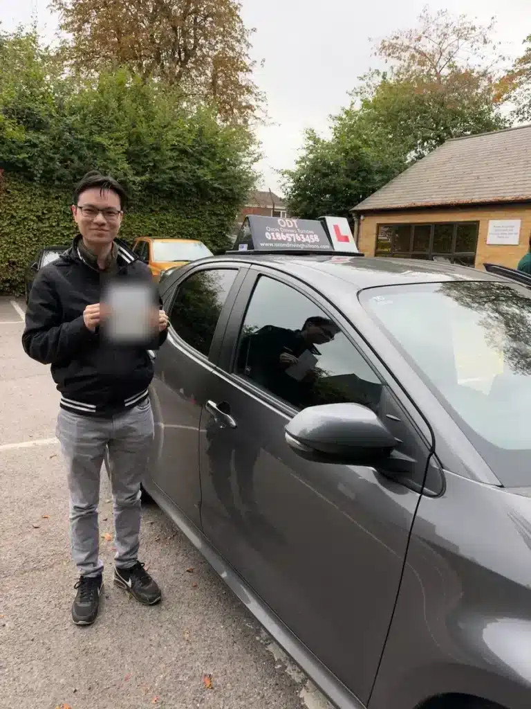 Summertown learner driver holding his driving test pass certificate beside an Oxon Driving Tuitions car