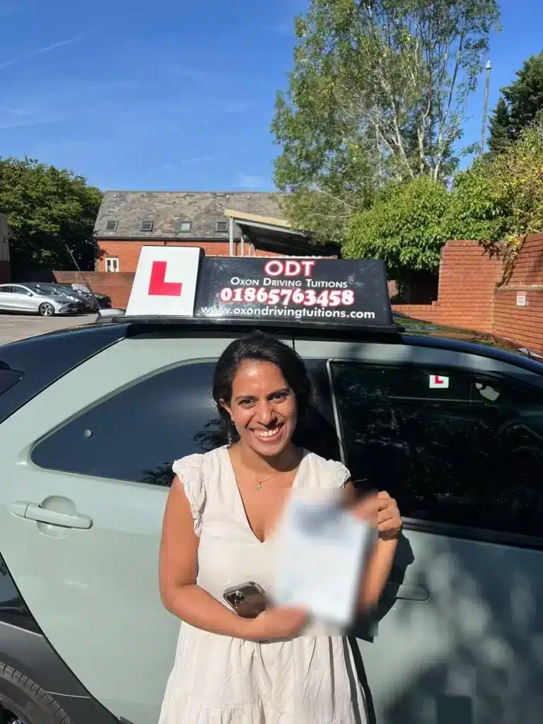 Smiling learner driver with her pass certificate beside an Oxon Driving Tuitions tuition car