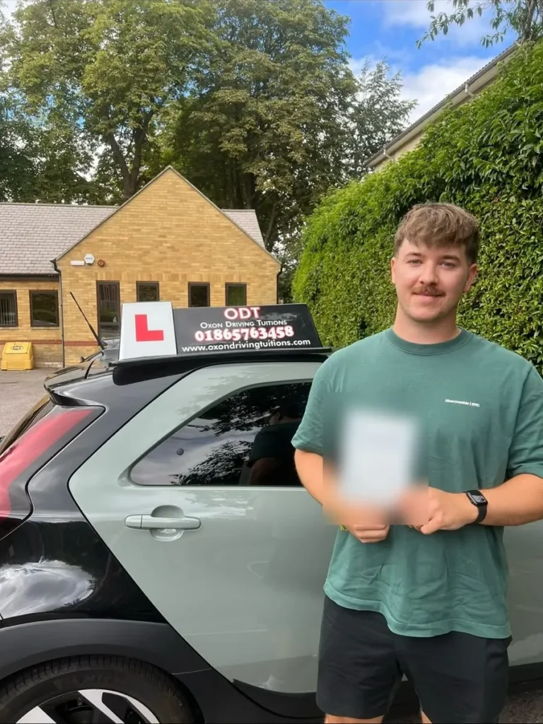 Learner driver with his practical driving test pass certificate next to an Oxon Driving Tuitions car