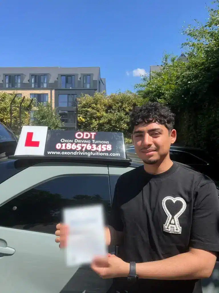 Learner driver holding her pass certificate in front of an Oxon Driving Tuitions car