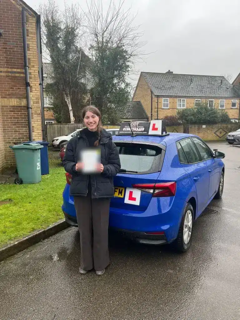 Learner driver holding her pass certificate beside an Oxon Driving Tuitions manual Skoda Fabia