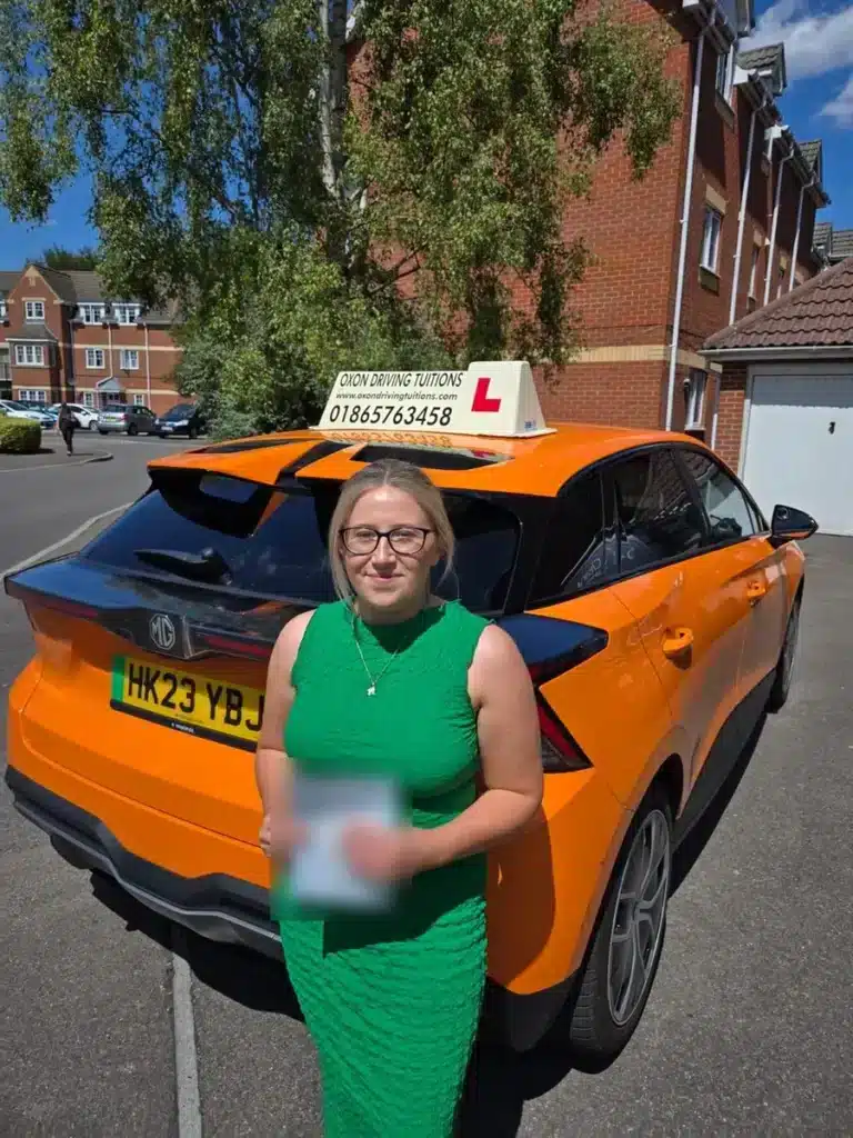 Learner driver with her pass certificate beside an Oxon Driving Tuitions electric MG4