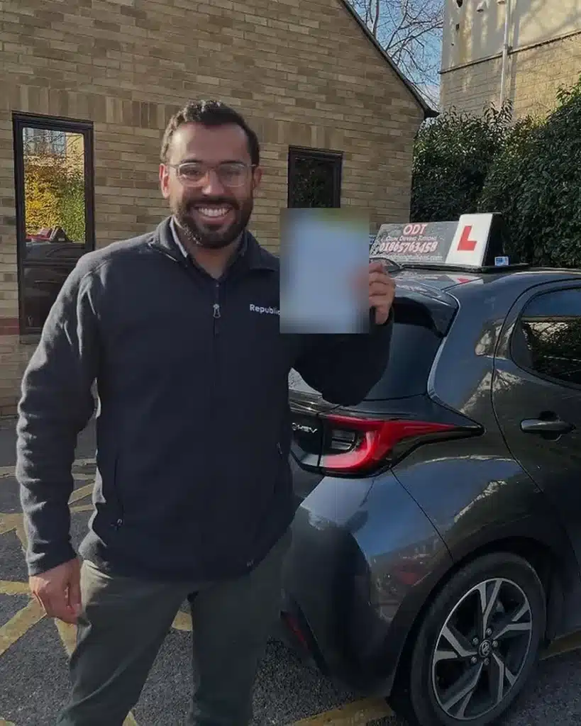 Botley learner driver smiling with his driving test pass certificate beside an Oxon Driving Tuitions automatic Toyota Yaris hybrid