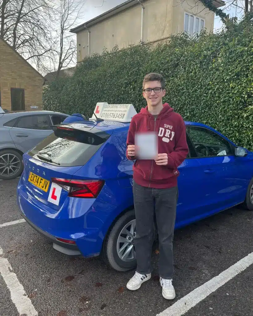 Botley learner driver holding his driving test pass certificate beside an Oxon Driving Tuitions Skoda