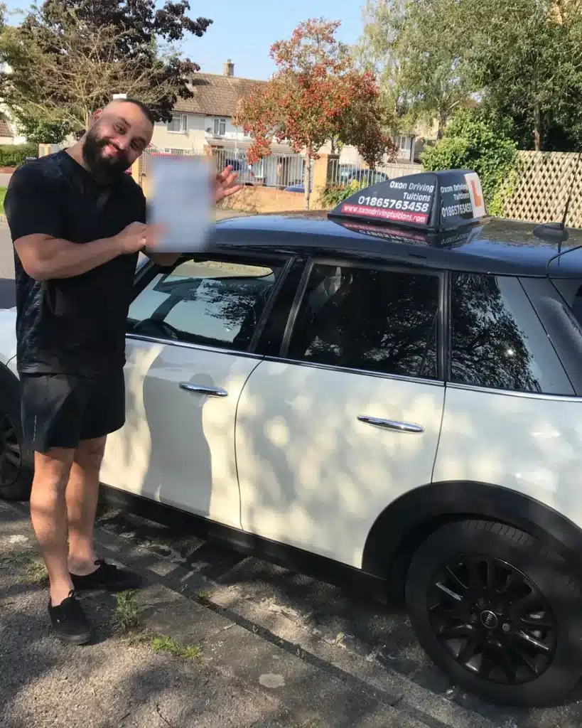 Cowley learner driver showing his driving test pass certificate beside an Oxon Driving Tuitions Mini
