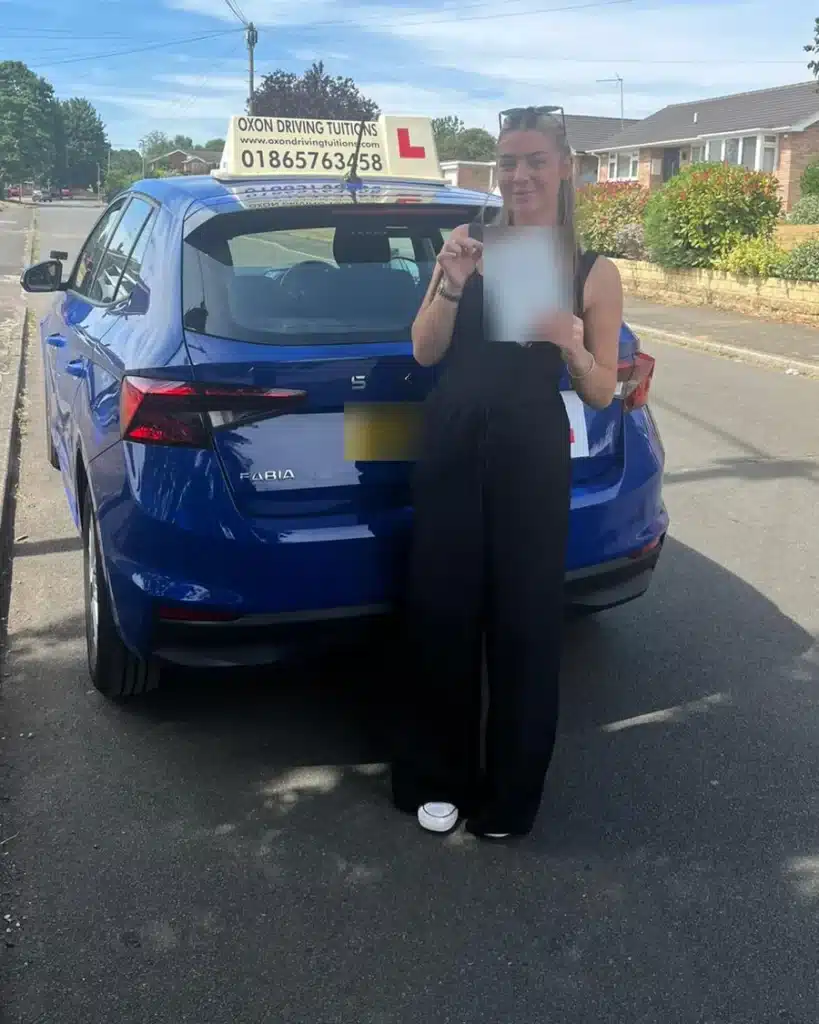 East Oxford learner driver holding her driving test pass certificate beside an Oxon Driving Tuitions Skoda Fabia