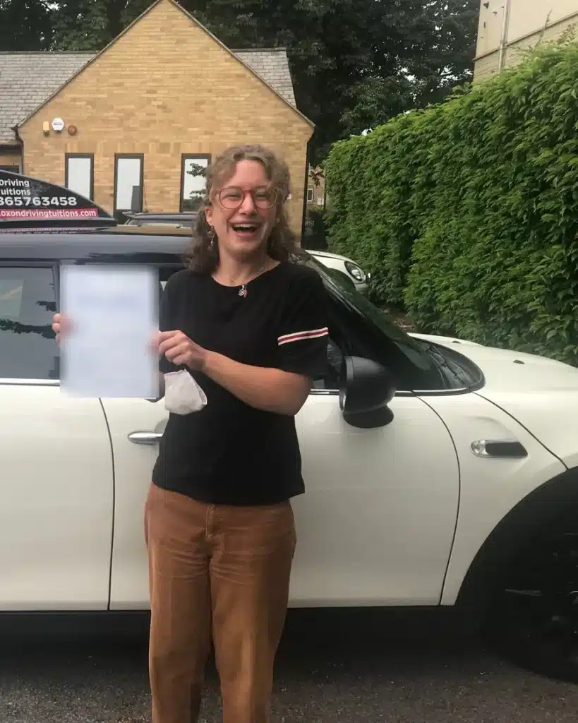 Headington learner driver laughing with her driving test pass certificate beside an Oxon Driving Tuitions Mini
