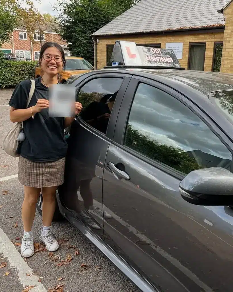 Jericho learner driver smiling with her driving test pass certificate beside an Oxon Driving Tuitions car