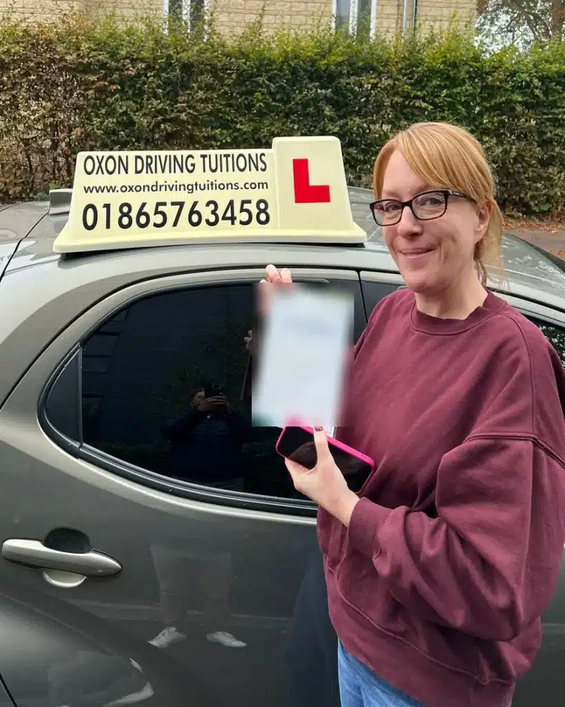 Cutteslowe and Sunnymead learner driver smiling with her driving test pass certificate beside an Oxon Driving Tuitions car