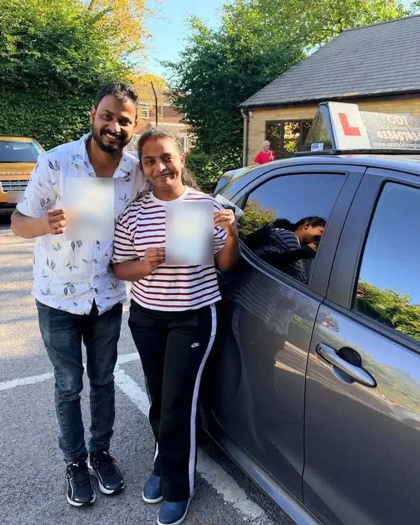 NHS staff couple smiling with their driving test pass certificates beside an Oxon Driving Tuitions car