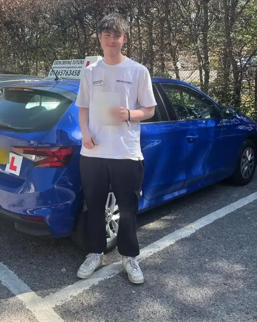 Student learner driver holding his driving test pass certificate beside an Oxon Driving Tuitions Skoda Fabia